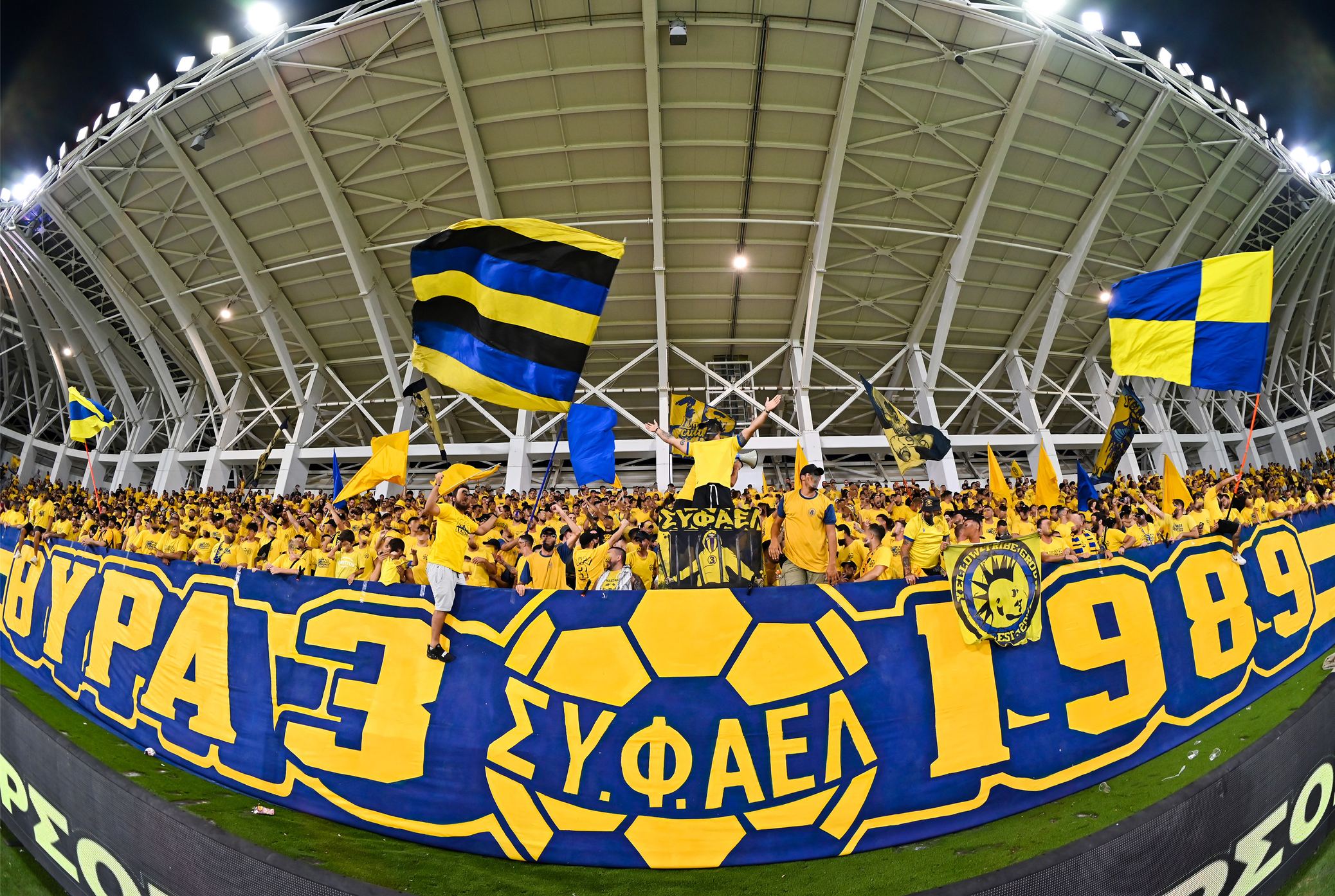 Home Οπαδοί της ΑΕΛ στην κερκίδα με σημαίες και κασκόλ του ΣΥ.Φ.ΑΕΛ